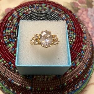 GOLD-TONE RING LARGE STONE IN THE CENTER AND THREE STONES EACH SIDE